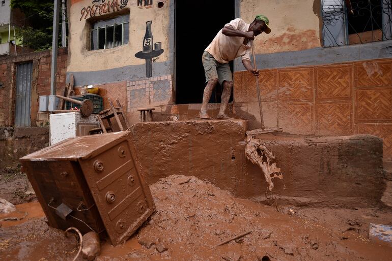 TOPSHOT - A man swabs down the mud left by the overflowing of Das Velhas River following torrential rains, in Sabara, in the metropolitan region of Belo Horizonte, Minas Gerais state, Brazil, on January 27, 2020. - The death toll from days of intense storms and flooding in southeastern Brazil has risen to 44, while the number of injured stands at 12 and that of the missing was lowered from 25 to 19, local Civil Defense officials said. (Photo by DOUGLAS MAGNO / AFP)