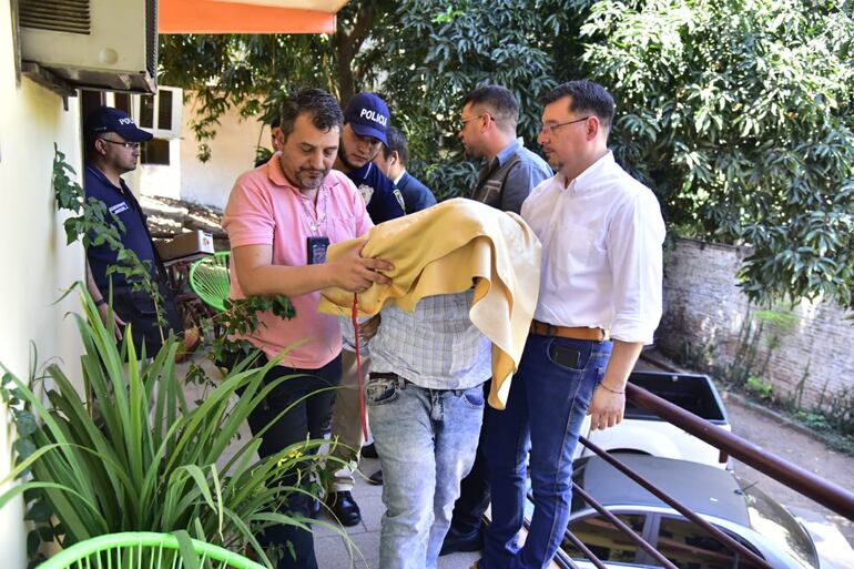 Los sospechosos son sacados con esposas del hotel.