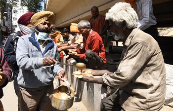 Voluntarios sirven comida para los necesitados durante el confinamiento dictado en la India para frenar la pandemia de coronavirus.