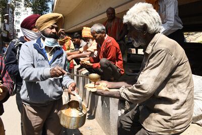 Voluntarios sirven comida para los necesitados durante el confinamiento dictado en la India para frenar la pandemia de coronavirus.
