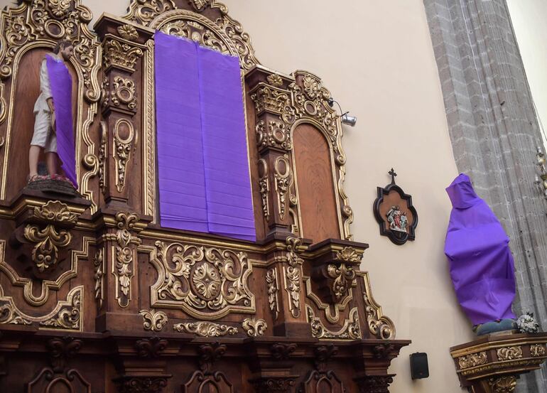Vista de imágenes religiosas femeninas cubiertas con telas de color púrpura en protesta contra la violencia hacia las mujeres en la iglesia de De los Santos Cosme y Damián en México.
