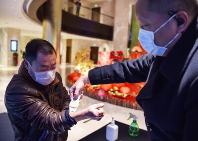 Un funcionario chino toma la temperatura a un pasajero en uno de los hoteles de la ciudad de Wuhan, epicentro del coronavirus.