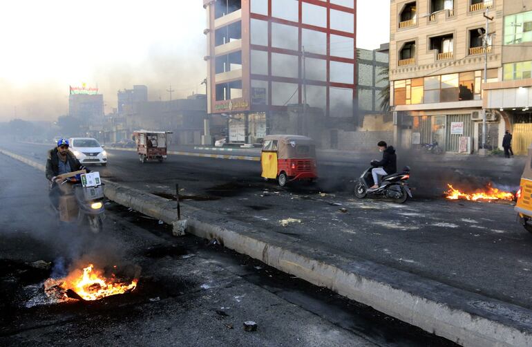 Conductores se desplazan entre las llamas de las protestas en Karbala, Irak.