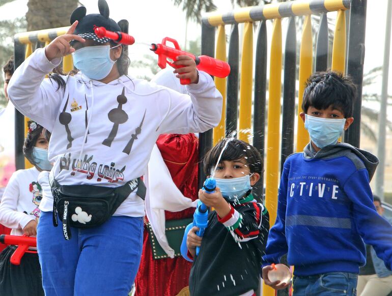 Niños con tapabocas juegan en la Ciudad de Kuwait.