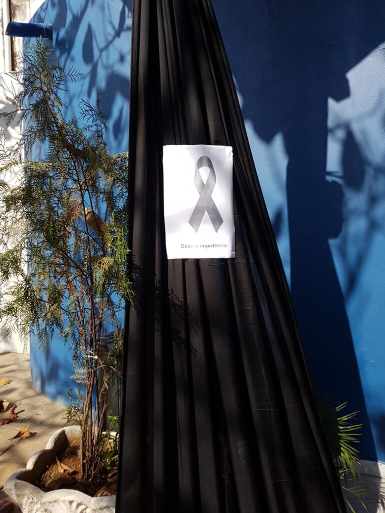 "Dolor e impotencia" reza un papel que lleva el símbolo de luto pegado a un poste en la escuela San Agustín.