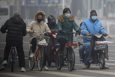 Las personas que usan máscaras protectoras andan en scooters y bicicletas en la calle en Beijing, China, el 13 de febrero de 2020.