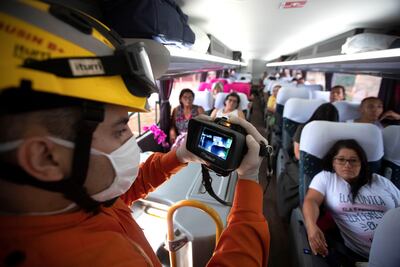 Bomberos usan cámaras térmicas y termómetros digitales para revisar a la ciudadanía mientras hacen un recorrido por los autobuses que llegan desde Sao Paulo este jueves a Brasilia (Brasil).