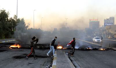 Manifestantes frente a una barricada humeante en una autopista de la ciudad de Karbala, Irak.