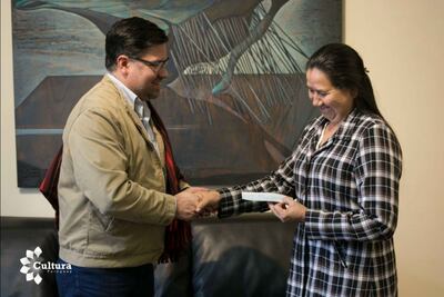 Rosa Segovia recibe de manos del Ministro Capdevila el cheque para las profesoras que enseñarán a realizar el poncho de sesenta listas