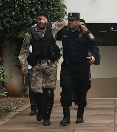Un efectivo policial ayuda al suboficial Ramón Peralta Collante a abandonar el lugar, ya con una venda en el ojo herido.