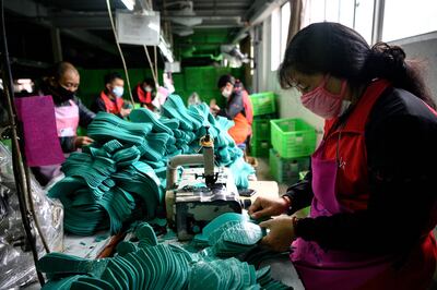 Esta foto de archivo tomada el 27 de febrero de 2020 muestra a los trabajadores que usan mascarillas protectoras como medida preventiva contra el coranavirus COVID-19, haciendo plantillas en la fábrica Zhejiang Xuda Shoes Co. en Wenzhou.
