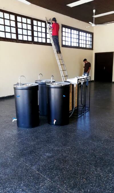 Los funcionarios de la firma Netsun realizan trabajos de instalación eléctrica frente a  lavatorios hechos de tambores.