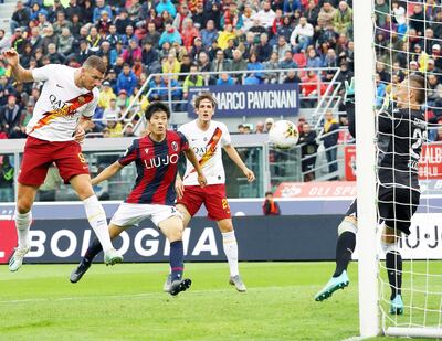 El bosnio Edin Dzeko salta y conecta  con golpe de cabeza, el balón para anotar el tanto de la victoria de la Roma sobre Bolonia por 2-1.