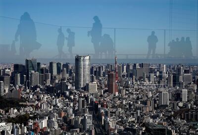 Las siluetas de varios turistas se reflejan sobre el paisaje urbano de Tokio (Japón), en una imagen tomada desde una azotea.