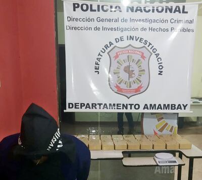 El detenido junto con los panes de cocaína incautados.