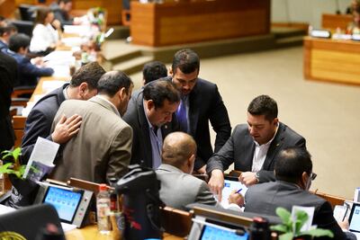 El titular de la Cámara de Diputados Pedro Alliana (ANR, cartista) dialoga con el líder de su bancada, Basilio Núñez, mientras otros legisladores los observan.