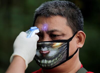 Un agente de policía toma la temperatura a un hombre que trata de cruzar un punto de control entre San Pedro y Mutinlupa en Gran Manila, Filipinas, este martes.