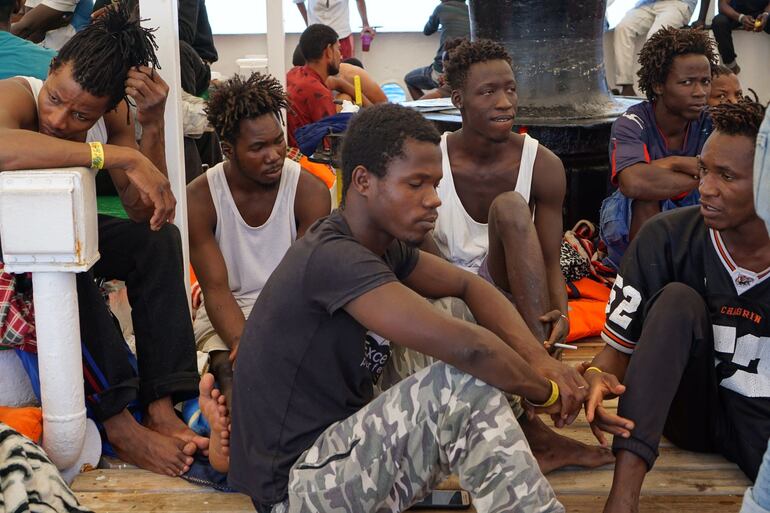 Varios migrantes a primera hora de este martes en el barco de la ONG española Open Arms, que sigue bloqueado desde hace 19 días frente a la isla italiana de Lampedusa.