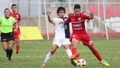 Marcos Benítez, de Tacuary, intenta puntear el balón a Luis Pereira, de Fernando de la Mora, ante la atenta mirada de la jueza Zulma Quiñónez, ayer en Atyrá.
