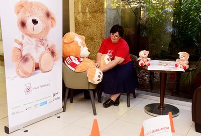 Una colaboradora de la campaña Relleno de Amor da una puntada para coser al osito “lastimado” y, así, reparar el daño. El mensaje invita a borrar las huellas de violencias hacia los niños.