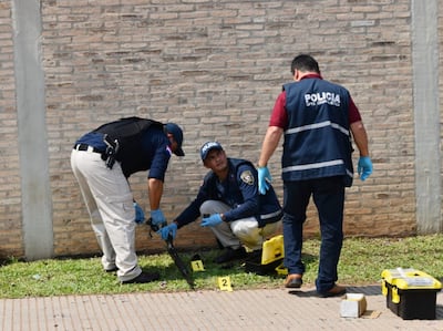 Efectivos policiales de Criminalística inspeccionan la escopeta que fue abandonada en el lugar del asalto por los delincuentes.