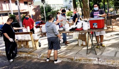 Siete voluntarios de la Pastoral Social de la parroquia Virgen del Rosario de Lambaré cargando  los recipientes para su distribución  posterior a las familias de escasos recursos de la zona.