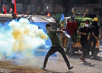 Un manifestante lanza una granada de gas lacrimógeno de vuelta a la policía en Bagdad.