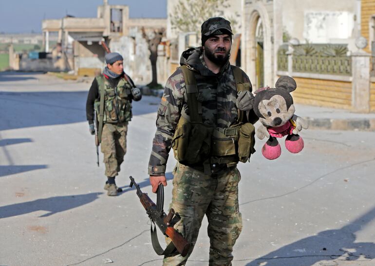 Un combatiente sirio con apoyo de Turquía camina con un juguete en Saraqib.