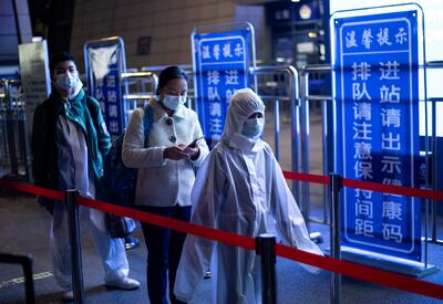 Personas con trajes de protección en una estación de trenes en Wuhan, China.