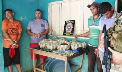 Los cuatro detenidos, esposados, junto a las bolsas repletas de marihuana y dosis de cocaína.