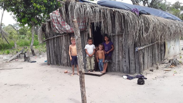 Niños indígenas de la comunidad "Ñande Yby Pave" frente a la choza en que viven.
