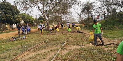 Jóvenes limpian las vías del tren en Pirayú.
