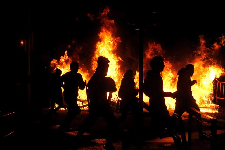 Manifestantes frente a una barricada en llamas en el centro de Barcelona, el jueves.