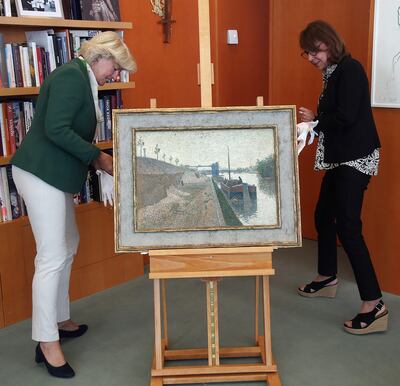 La ministra germana de Cultura, Monika Gruetters observa la pintura "Quai de Clichy", del neo impresionista Paul Signac, que fue devuelta a Agnes Sevestre-Barbe.