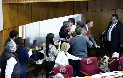 Enrique Riera es atajado por varios legisladores y funcionarios de la Cámara Alta mientras Paraguayo Cubas se encuentra tirado en el piso tras la embestida del primero.