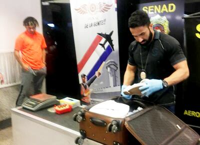 Un agente especial de la Senad verifica los paquetes de cocaína mientras el detenido Julio Estiven Cáceres aguarda el resultado.