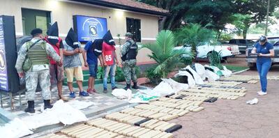 Los cuatro detenidos junto con los panes de marihuana prensada hallados en poder de los mismos.