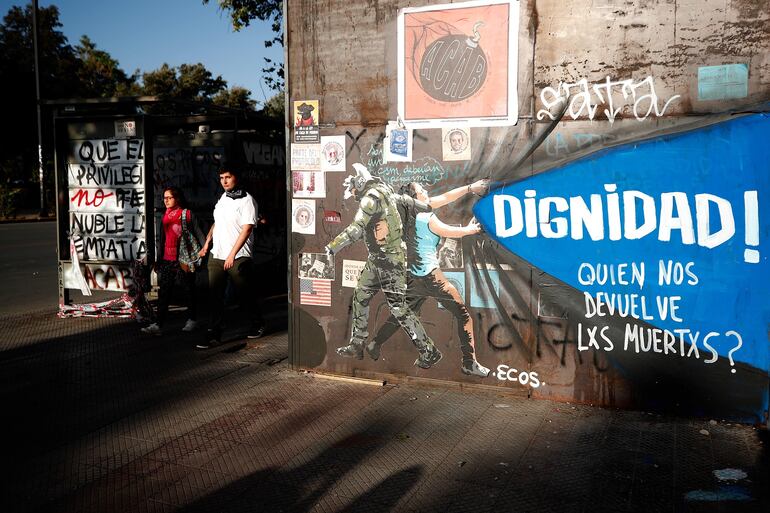 Una pareja camina este domingo en la céntrica plaza Italia de Santiago (Chile), rebautizada popularmente como Plaza de la Dignidad.
