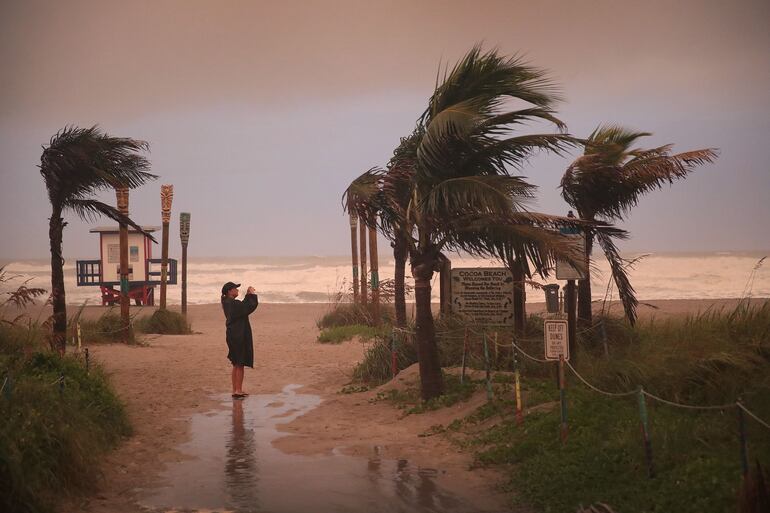 Una mujer toma una fotografía en la playa Cocoa, en Florida. 