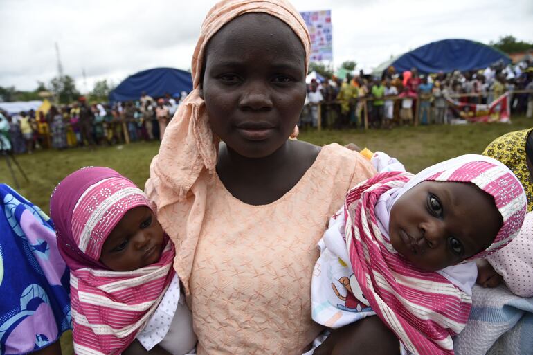 Una mamá carga a sus gemelos durante el festival Igbo-Ora.