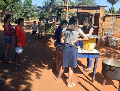La gente forma fila para llevar comida a sus hogares. En el asentamiento viven 650 niños de familias de escasos recursos.