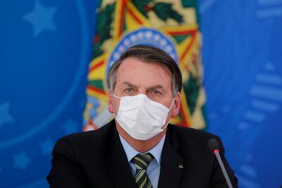 El presidente brasileño, Jair Bolsonaro, se cubre el rostro con una máscara facial durante una conferencia de prensa sobre la pandemia del COVID-19 en el Palacio de Planalto, Brasilia / 18 de marzo de 2020.