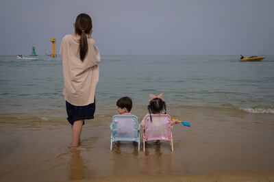 Una mamá y sus dos hijos miran el mar en la playa de Sokcho, en Corea del Sur. Los chicos están listos para volver a las clases.