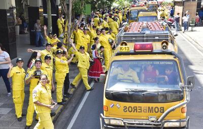 Bomberos voluntarios saludan el paso de los carros hidrantes, las  ambulancias y otros móviles.