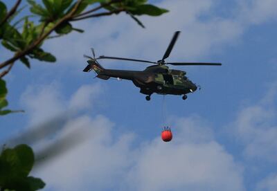 Un helicóptero militar lleva agua para sofocar un punto de incendio en la localidad de Roboré, Bolivia.