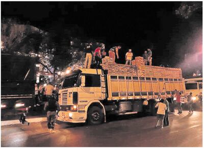 Momento en que los comerciantes informales y otras personas revisan uno de los camiones retenidos en la frontera.