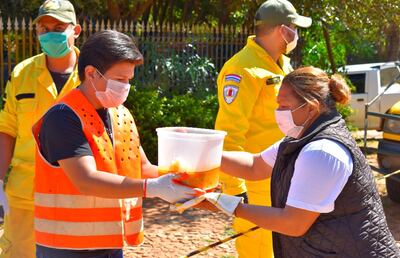 Bomberos voluntarios ordenaron a las personas que se acercaron para retirar  alimentos en el barrio San Miguel.