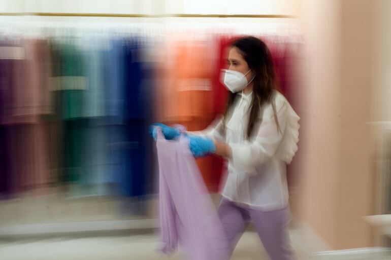 Una empleada con mascarilla en un comercio de ropas en Madrid, España.