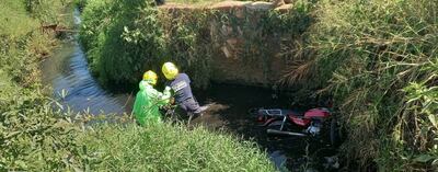 Bomberos retiran del cauce hídrico el cuerpo sin vida de Aurelio Almada Martínez. A su lado, la motocicleta que fue denunciada como robada.