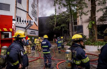 AME977. ASUNCIÓN (PARAGUAY), 29/09/2022.- Bomberos realizan trabajos este jueves dentro de la sede del Tribunal Superior de Justicia Electoral en Asunción (Paraguay). Un incendio se desató este jueves en un edificio del TSJE de Paraguay, donde se estima permanecían unas 8.500 máquinas de votación destinadas a los comicios partidarios internos del próximo 18 de diciembre, lo que generó de inmediato llamados de sectores políticos a investigar la situación. Los bomberos han tenido que trabajar durante más de 7 horas y tuvieron que abrir boquetes en la edificación para combatir el incendio. EFE/ Nathalia Aguilar